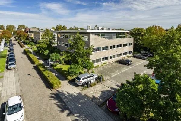 Kantoorgebouw aan de Jan Leentvaarlaan met parkeerplaatsen en omliggend groen op een zonnige dag.